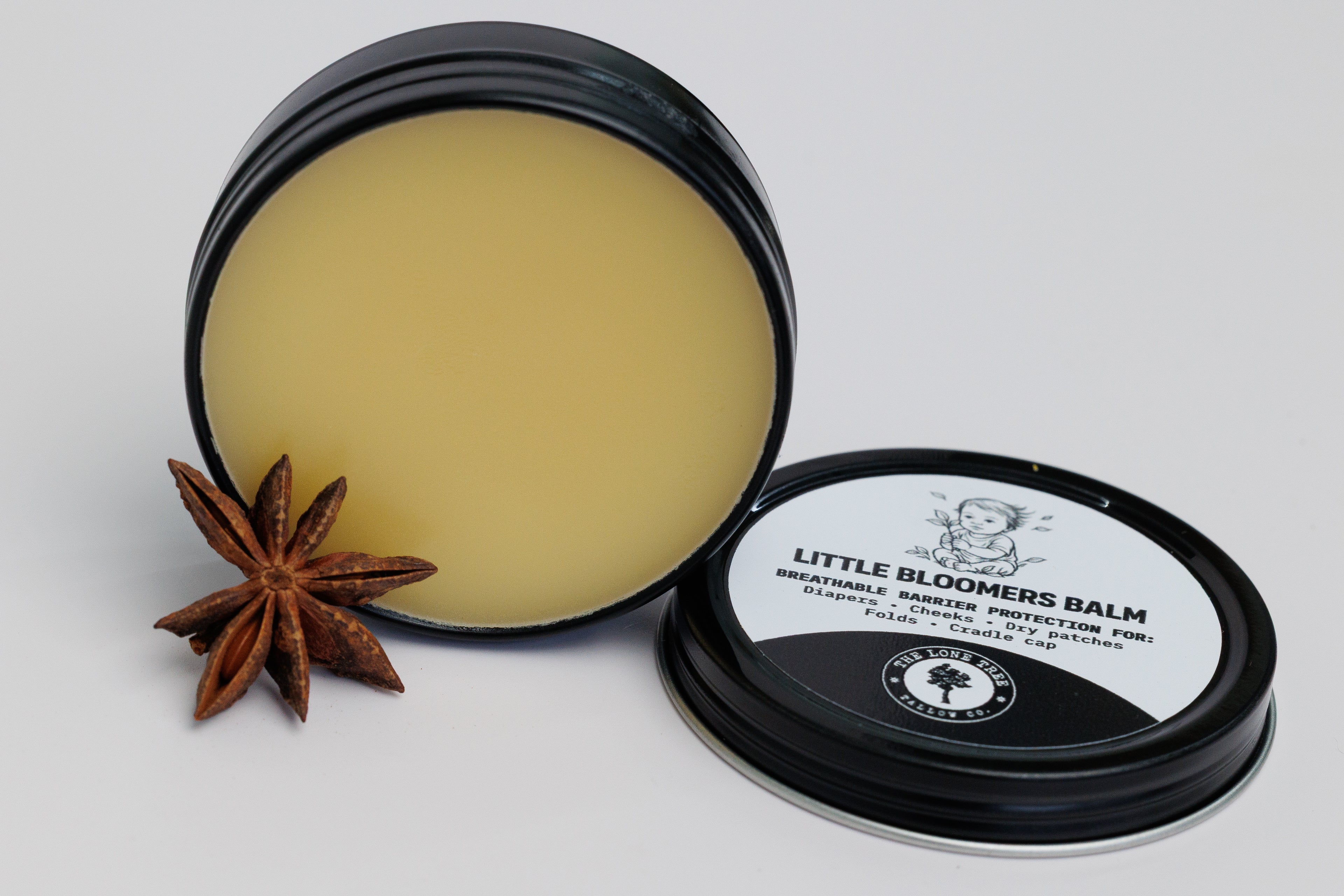 Open lid showing color and texture of Little Bloomers Balm from Lone Tree Tallow Co. in a 2 oz black tin. used for diapers, cradle cap and dry patches. safe for babies. pure heritage tallow, calendula infused sunflower oil, vitamin E. no essential oils. pure and natural. 