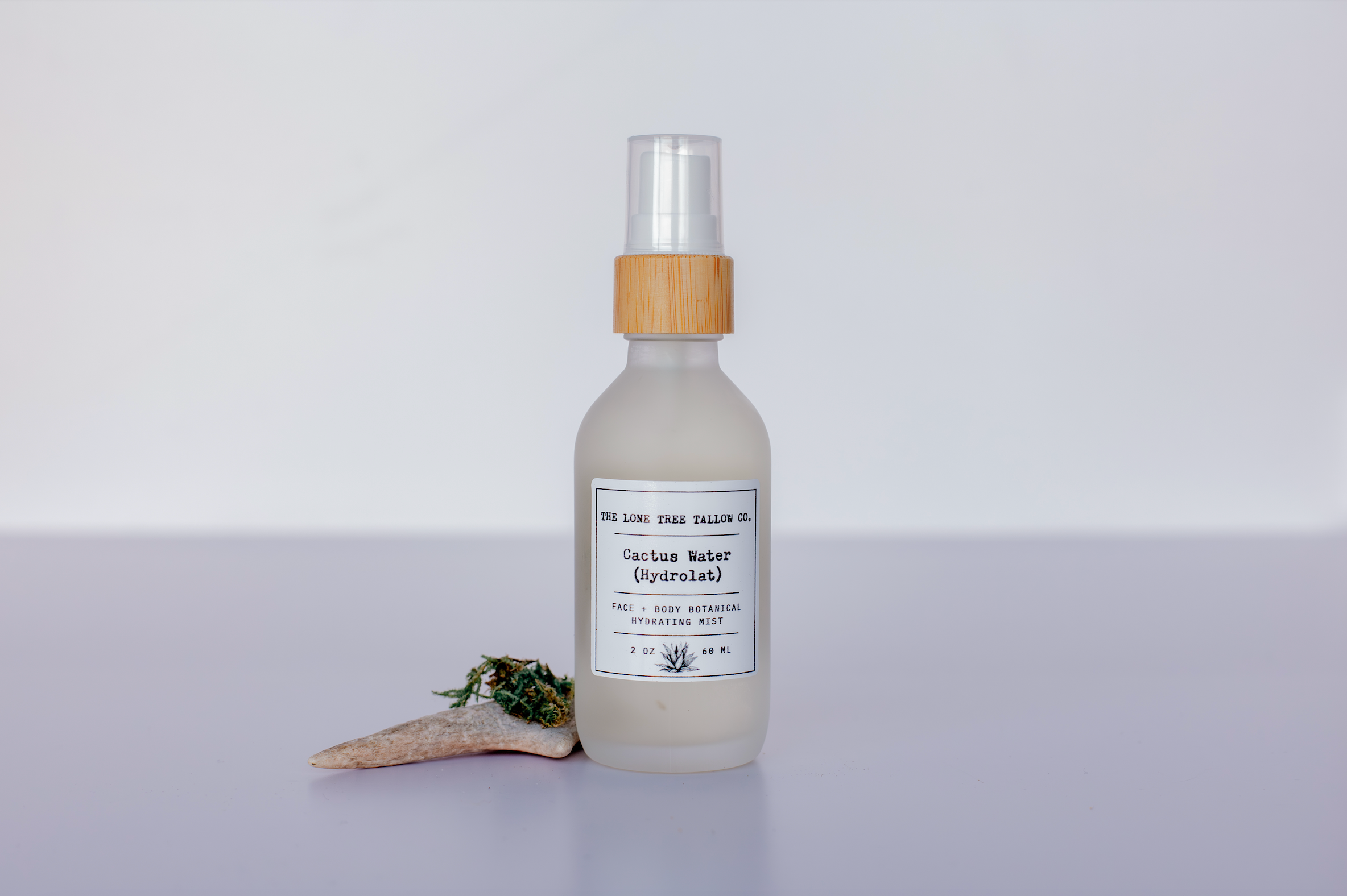a picture of lone tree tallow co. cactus water hydrolat in a 2 oz frosted white glass spray bottle with a bamboo top. 
